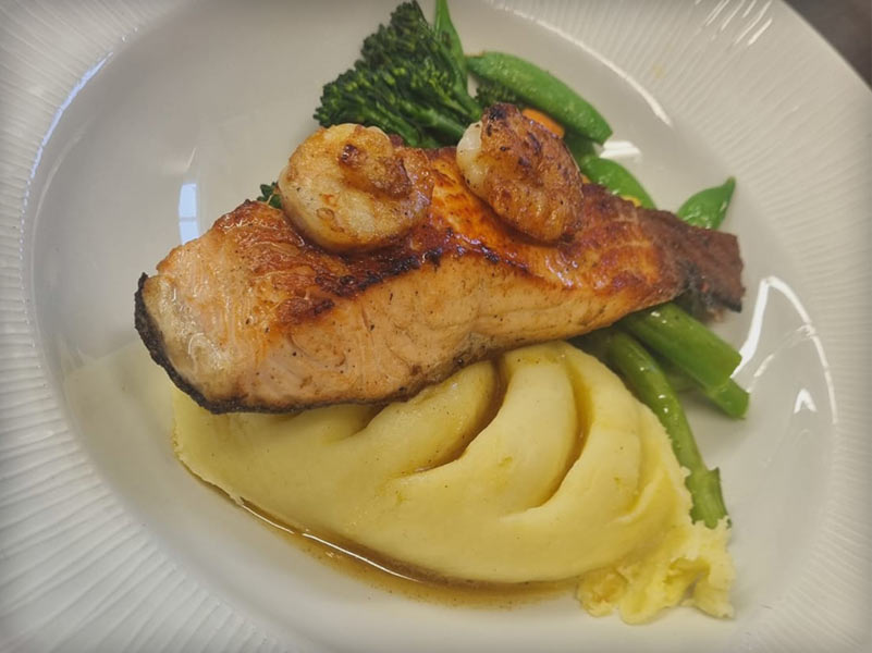 Delicious Salmon & Tiger Prawns with a chilli butter, accompanied by mashed potatoes and our delicious seasonal vegetables